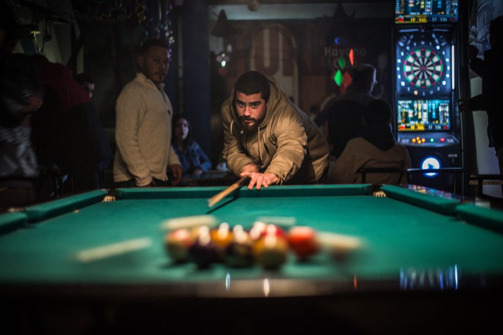A man playing a game of pool. Alcohol and fun and games!