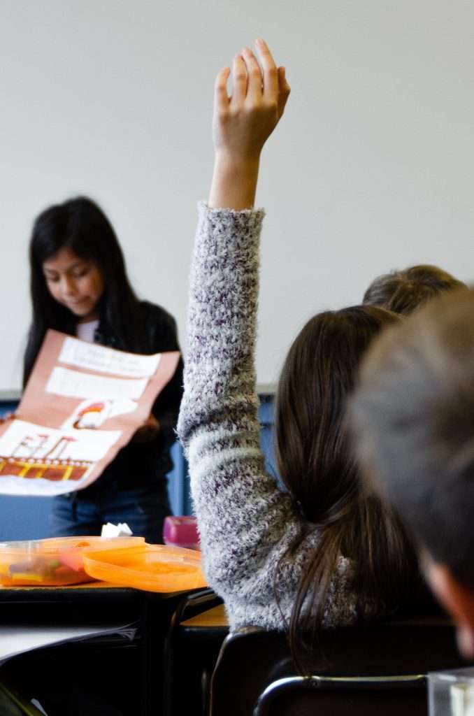 A girl in her childhood raising her hand in class